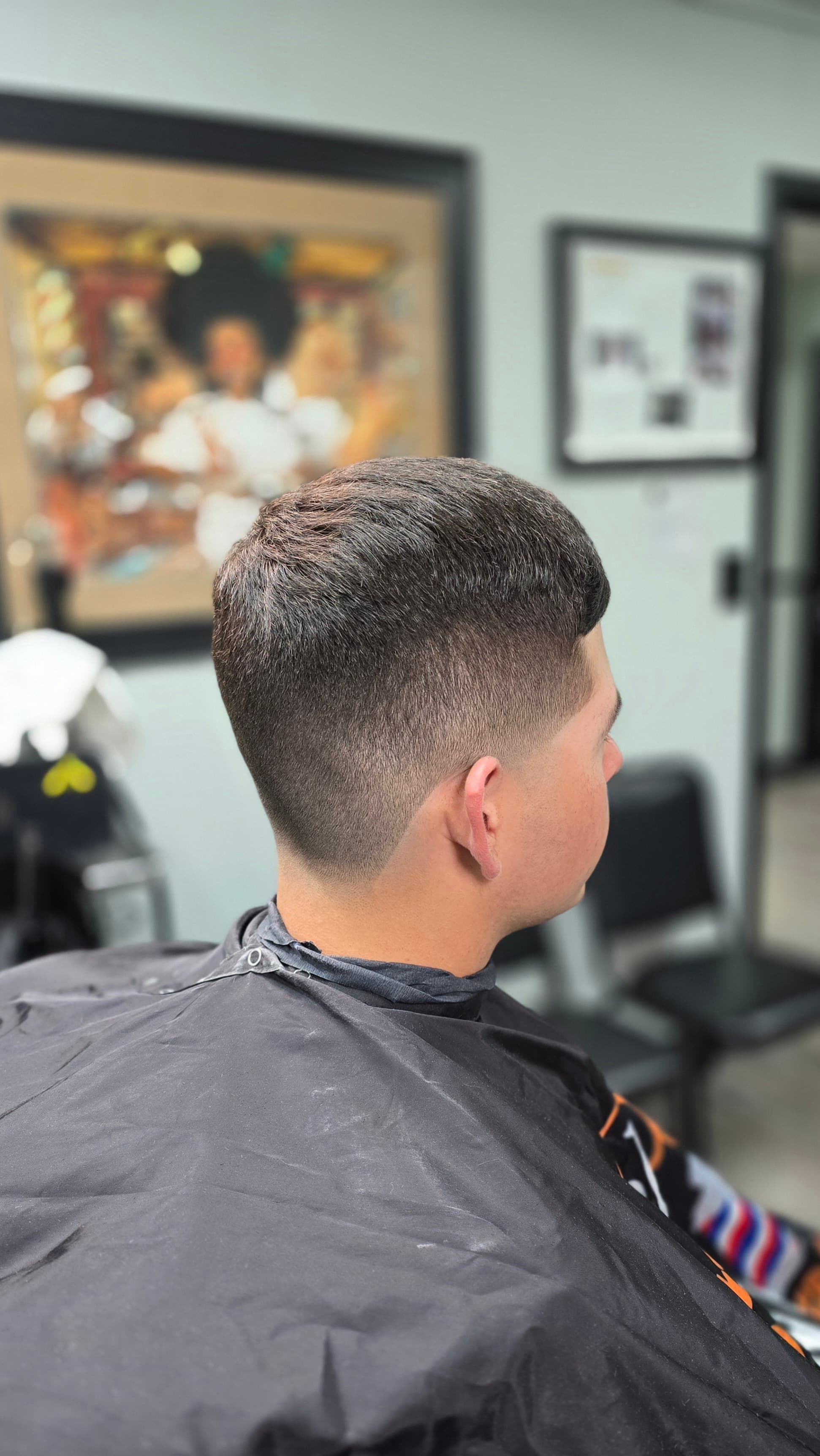 Man with a clean skin fade haircut and short textured top in a barbershop.