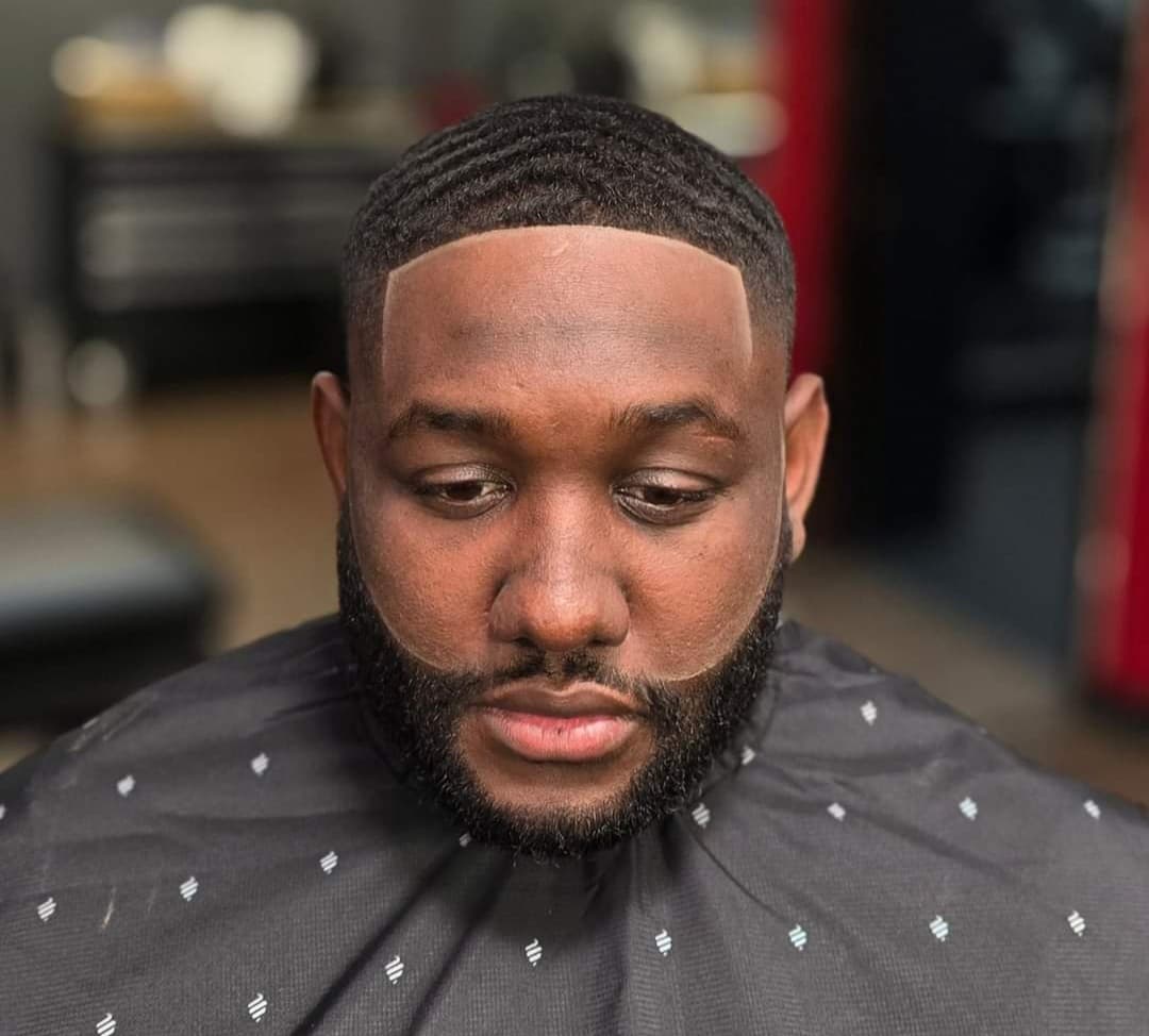Black man with 360 waves and a sharp, fresh line-up on his hair and beard.